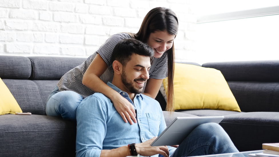 Two people sitting down and looking at a tablet screen