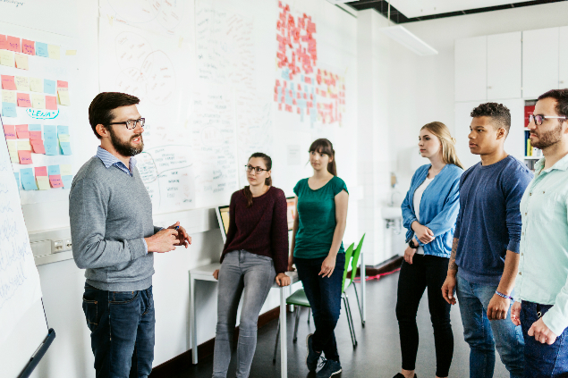 Teacher stands in front of students in a classroom.