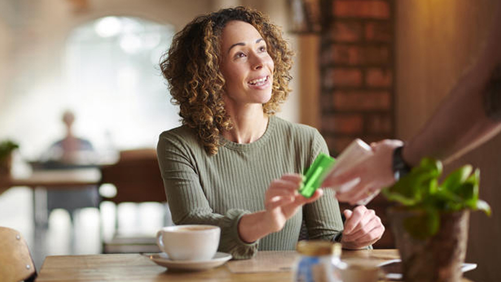 Smiling women paying for her coffee at a cafe using a Citizens contactless card