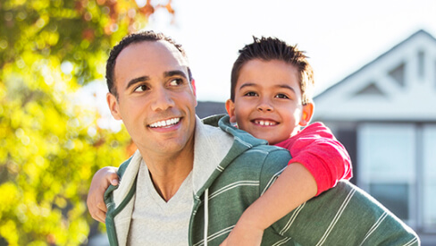 Man carrying small child on his back