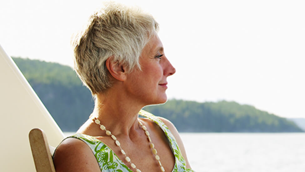 Older woman sitting in a chair outside looking out over the water