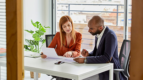 Two people sitting at a desk, looking over documents