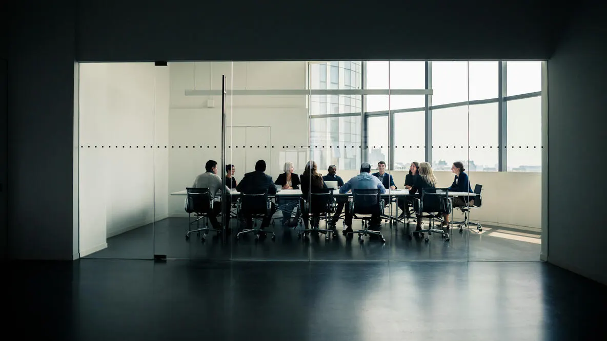 A large group of people holding a meeting in an office.