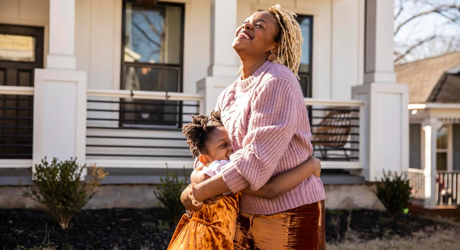 A mother and daughter hugging outside their home