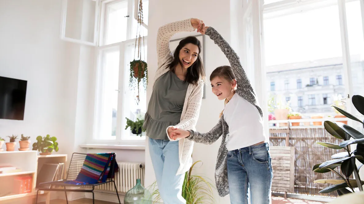 Mother and daughter dancing in their home.
