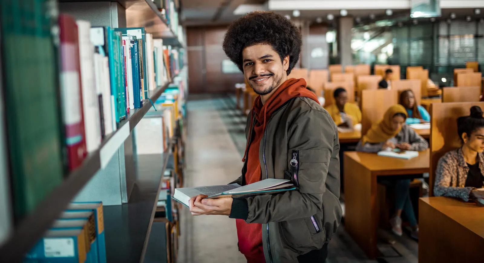 young man holding a book in a library
