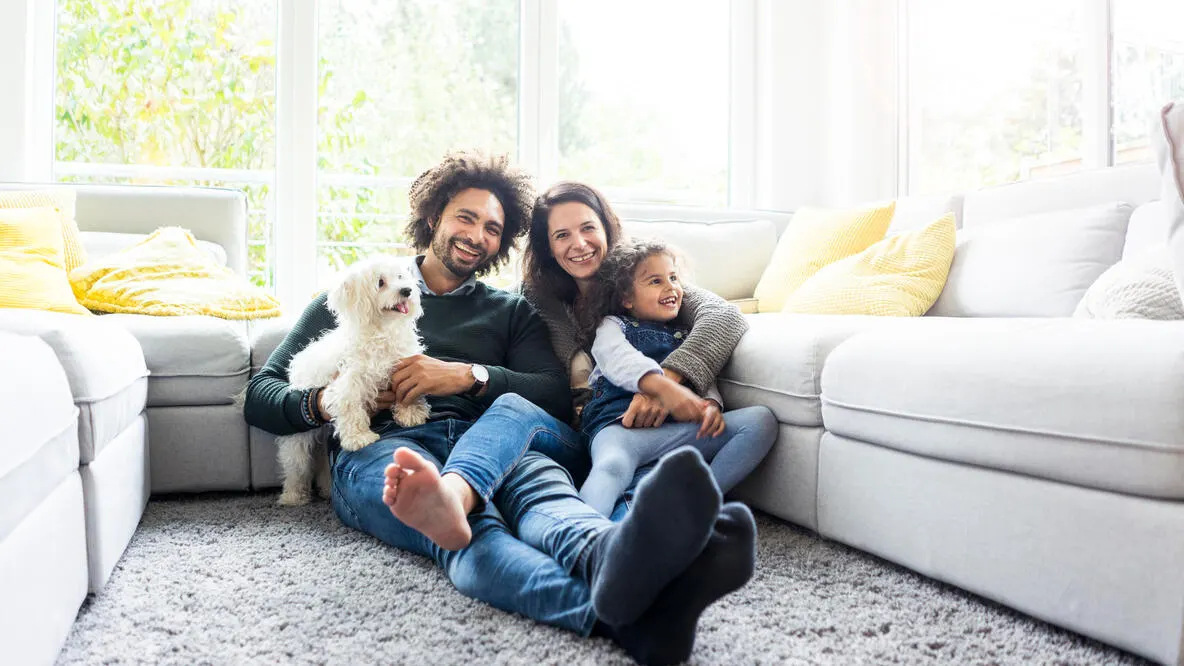 A family sitting on the floor playing with their puppy.