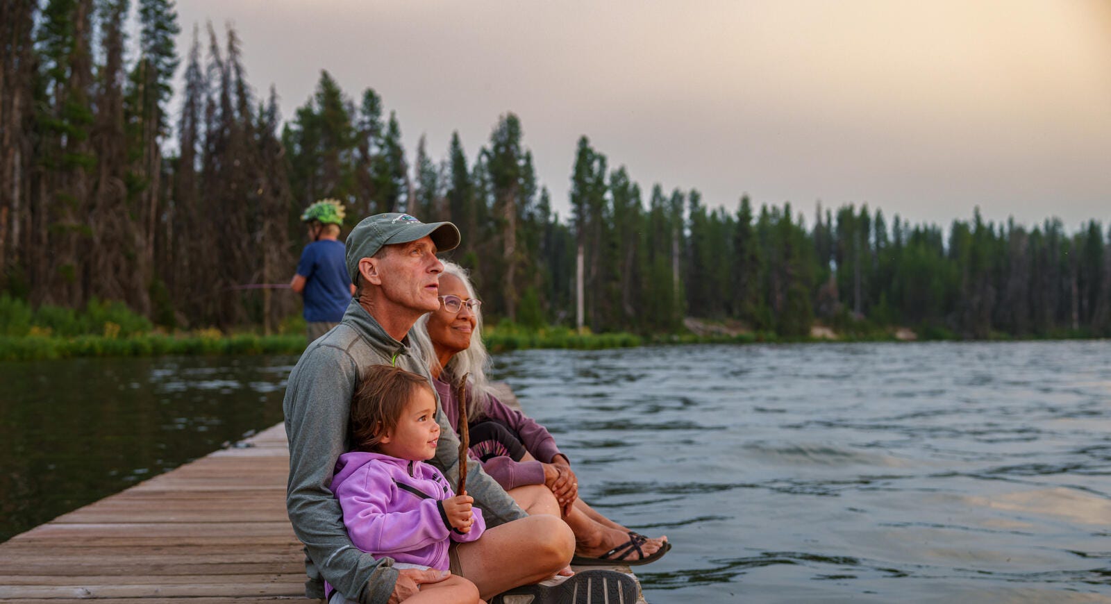 A family sitting on a dock enjoying the sunset.