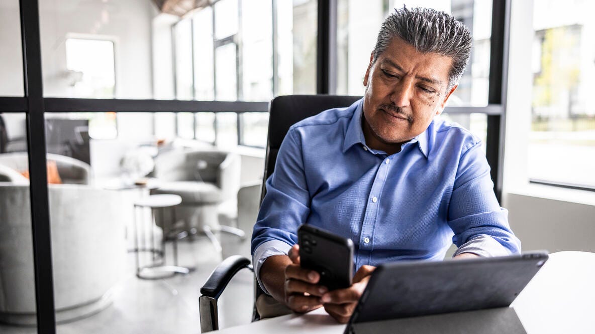 Hombre mayor utilizando su teléfono celular en un ambiente de trabajo informal