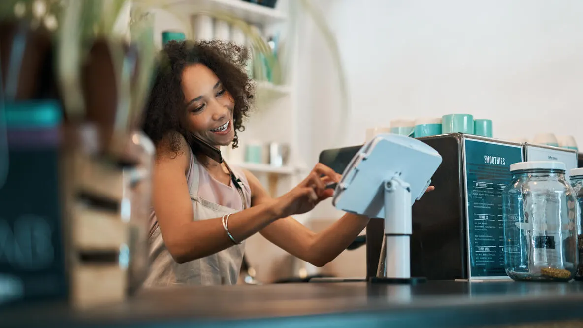 A young woman using a smartphone while working in a coffee shop.