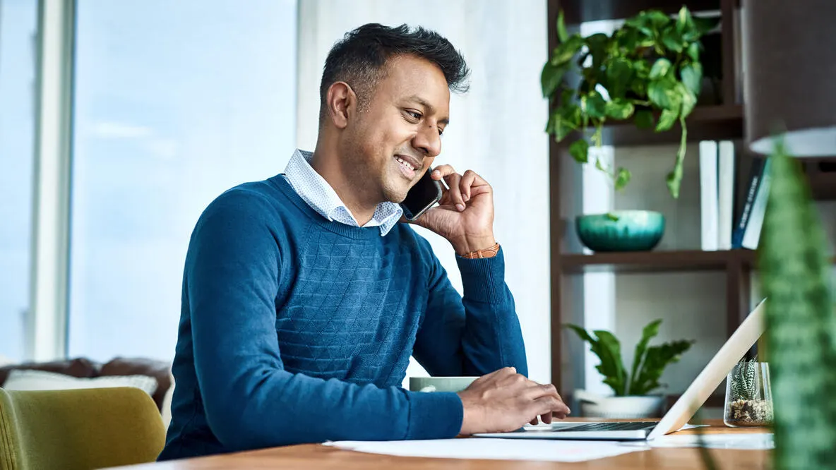 A person sitting at a desk in front of a laptop
