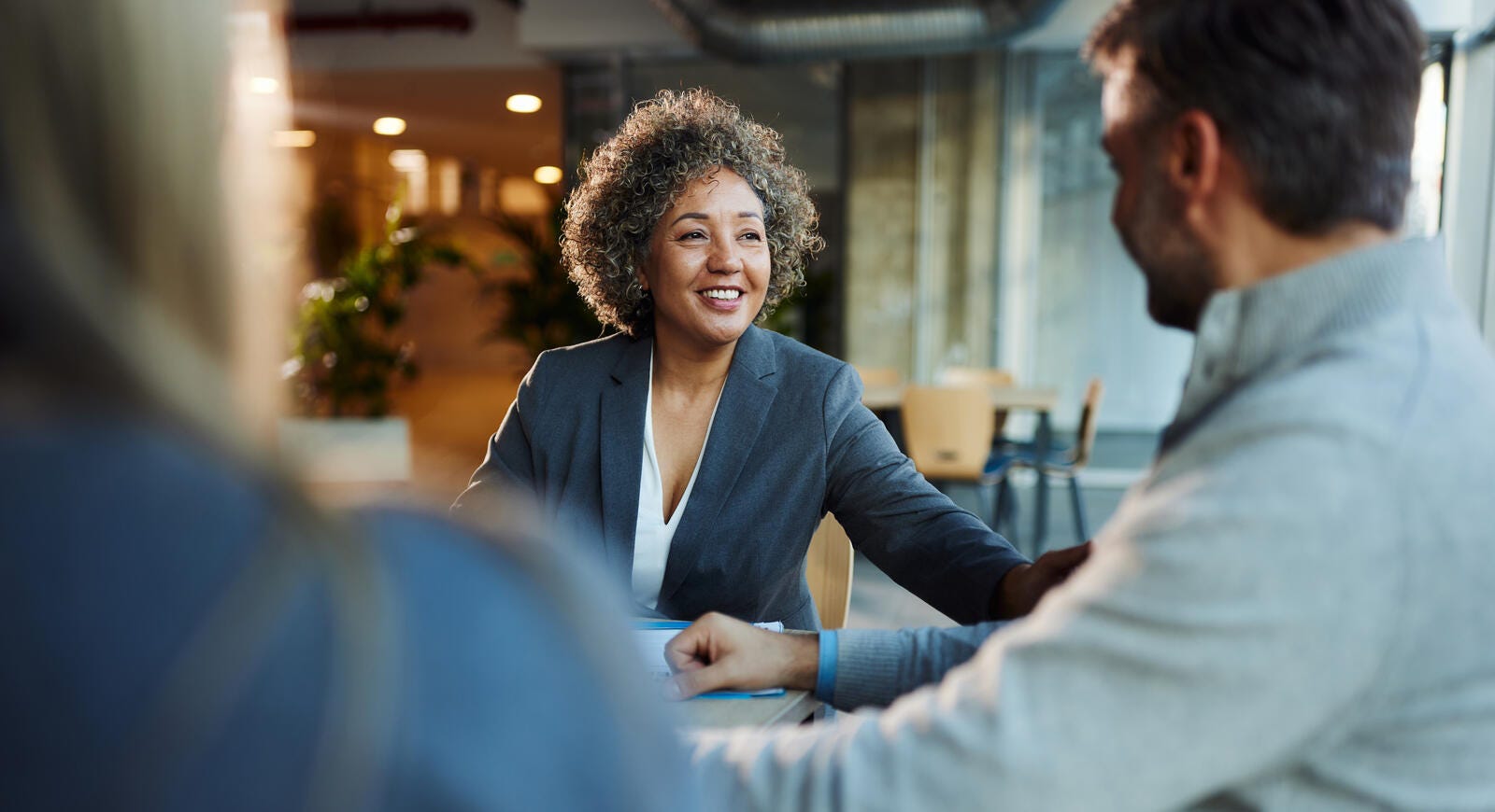 A couple sitting a table talking to an insurance specialist.