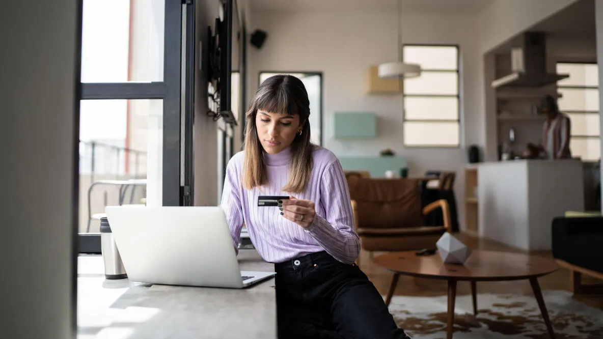 A person sitting at a desk in front of a laptop holding a card