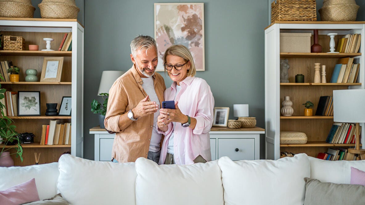 A couple smiling while lookig at a smart phone.