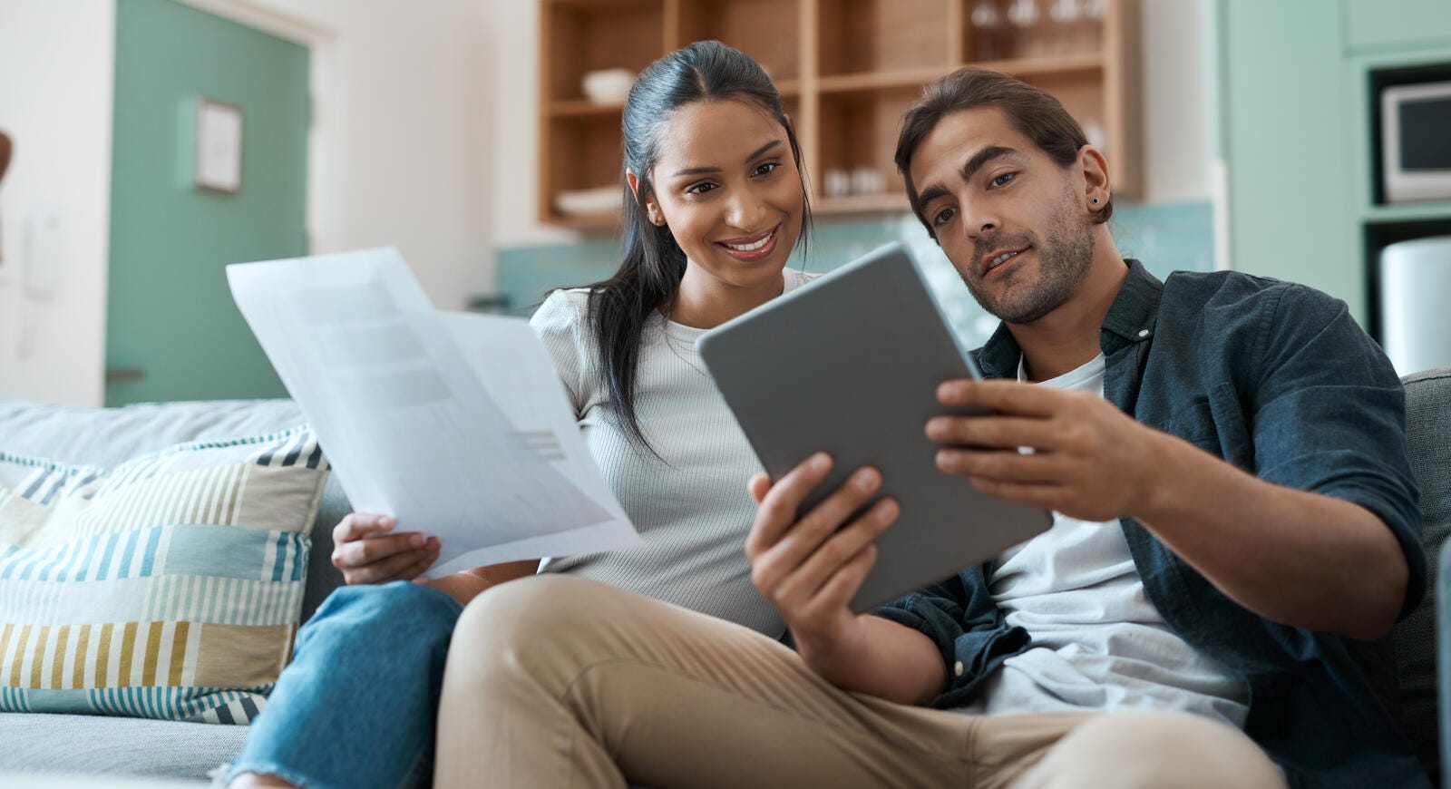 Dos adultos de mediana edad usando una Tablet y revisando unos papeles.