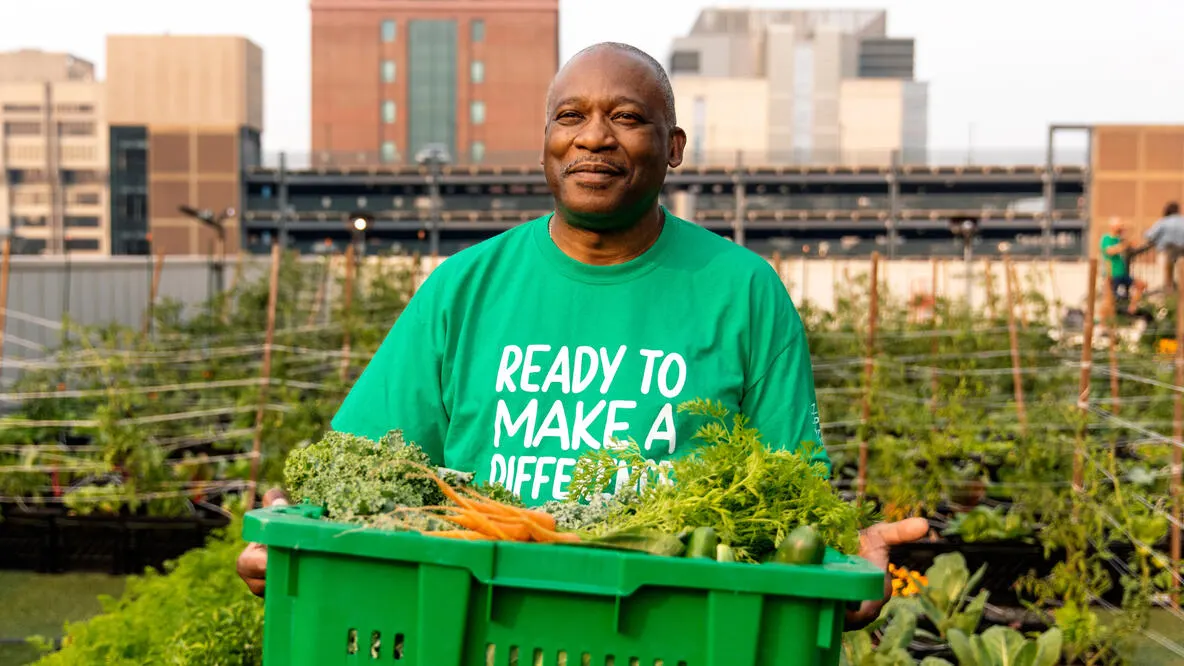 a man holding a crate of vegetables