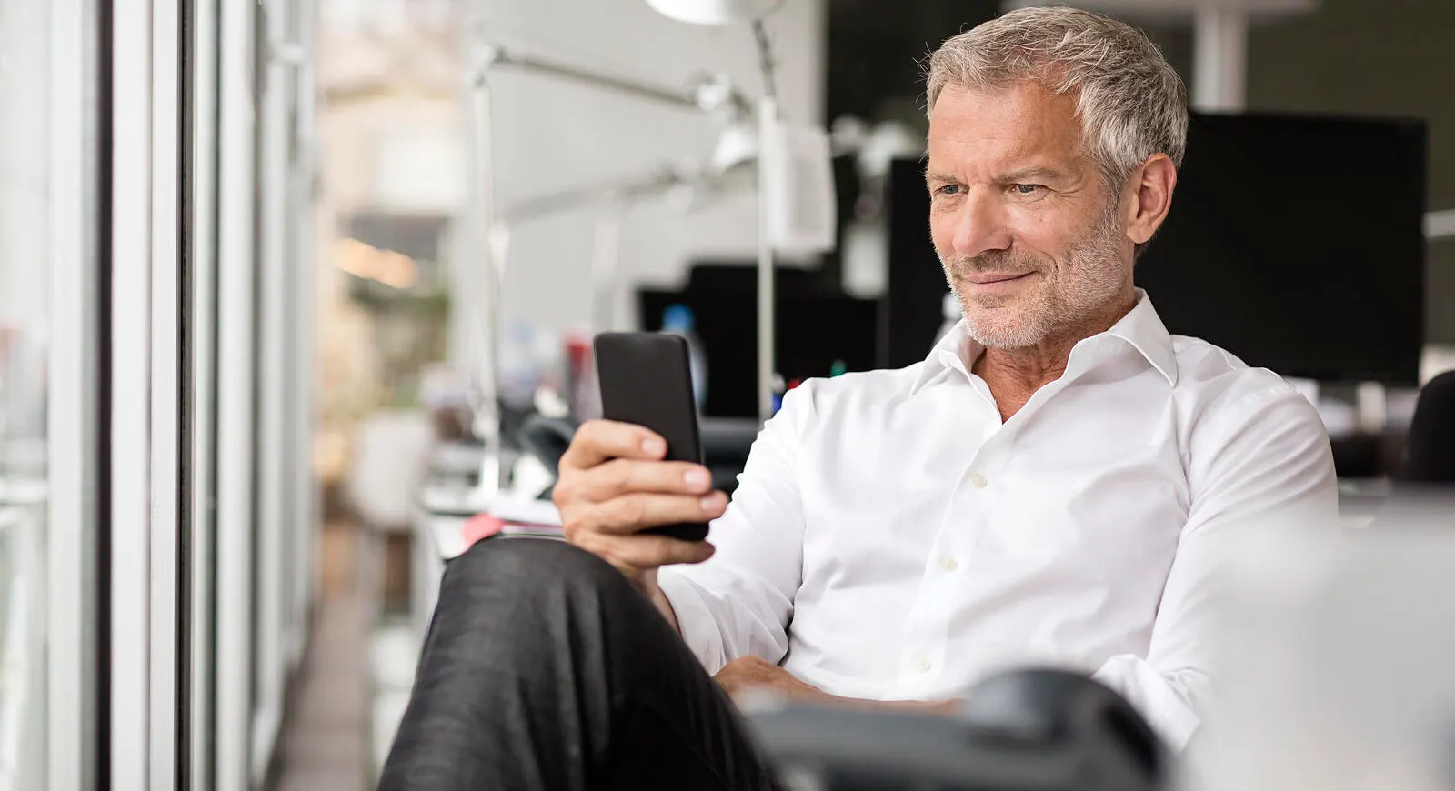 A man sitting in an office using his smart phone