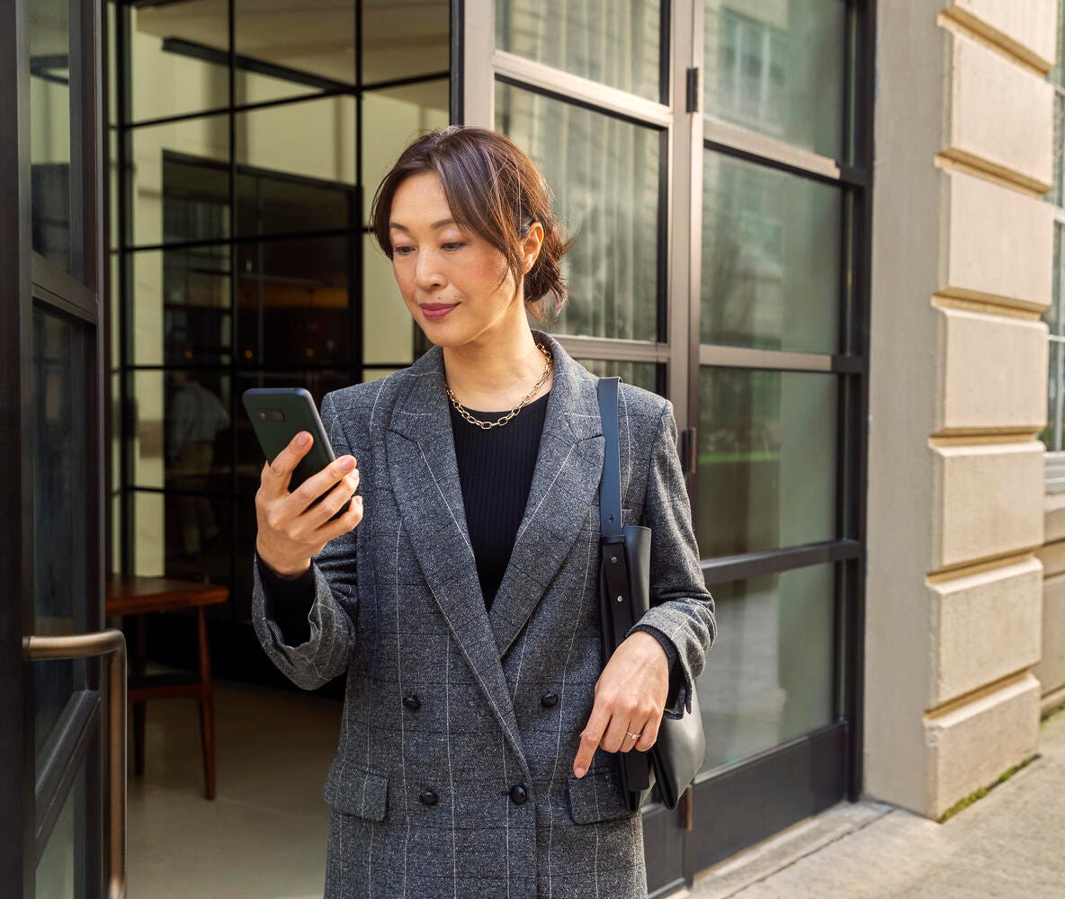 Woman walking on sidewalk while looking at phone