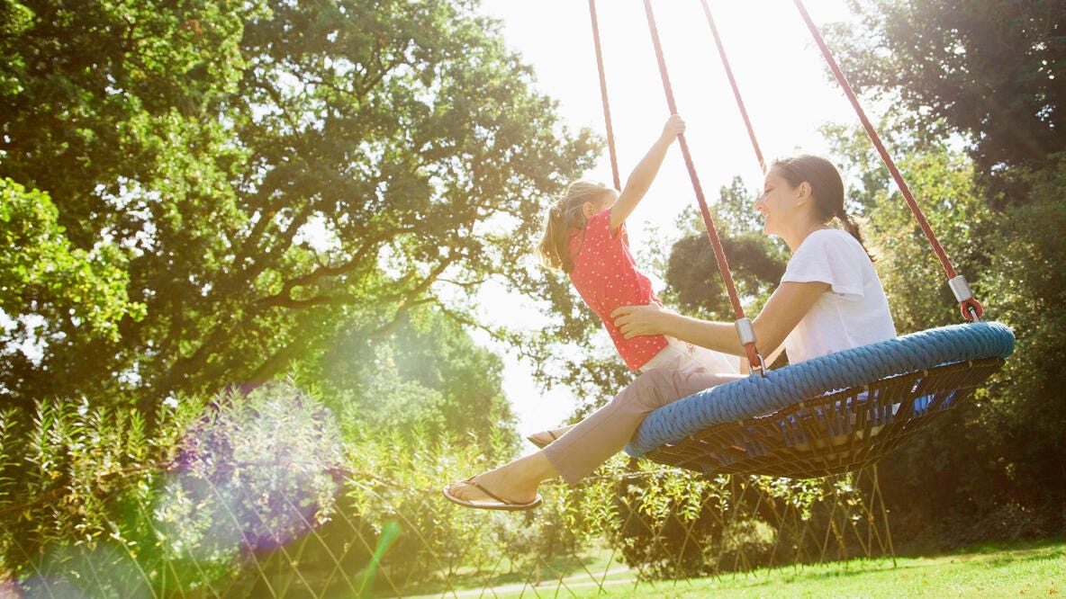 Mom and a child swinging on a swing.