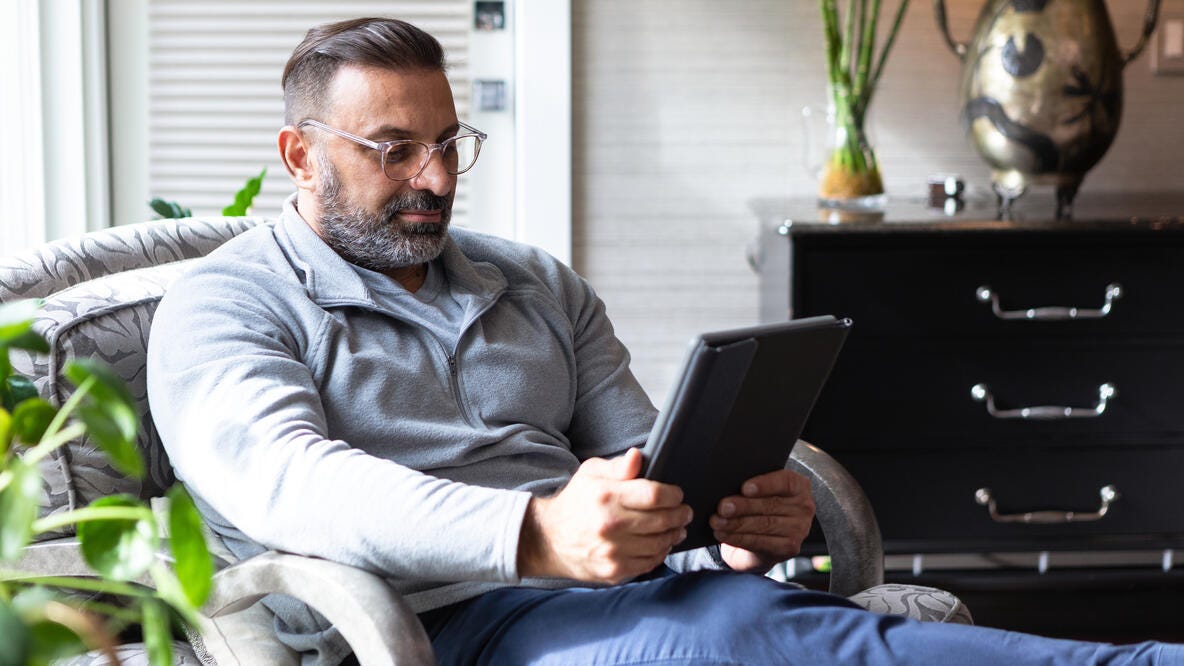 Hombre de mediana edad usando una Tablet en un sillón.