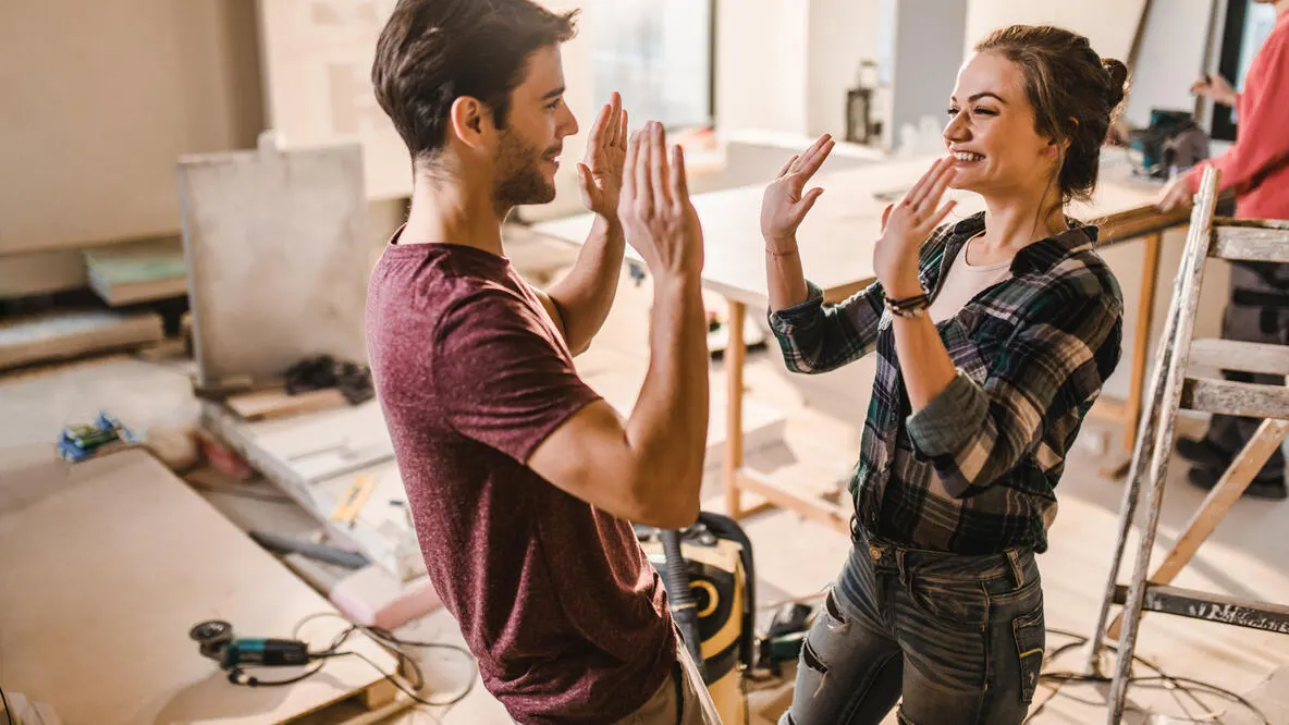 A couple giving each other ten while renovating a home.