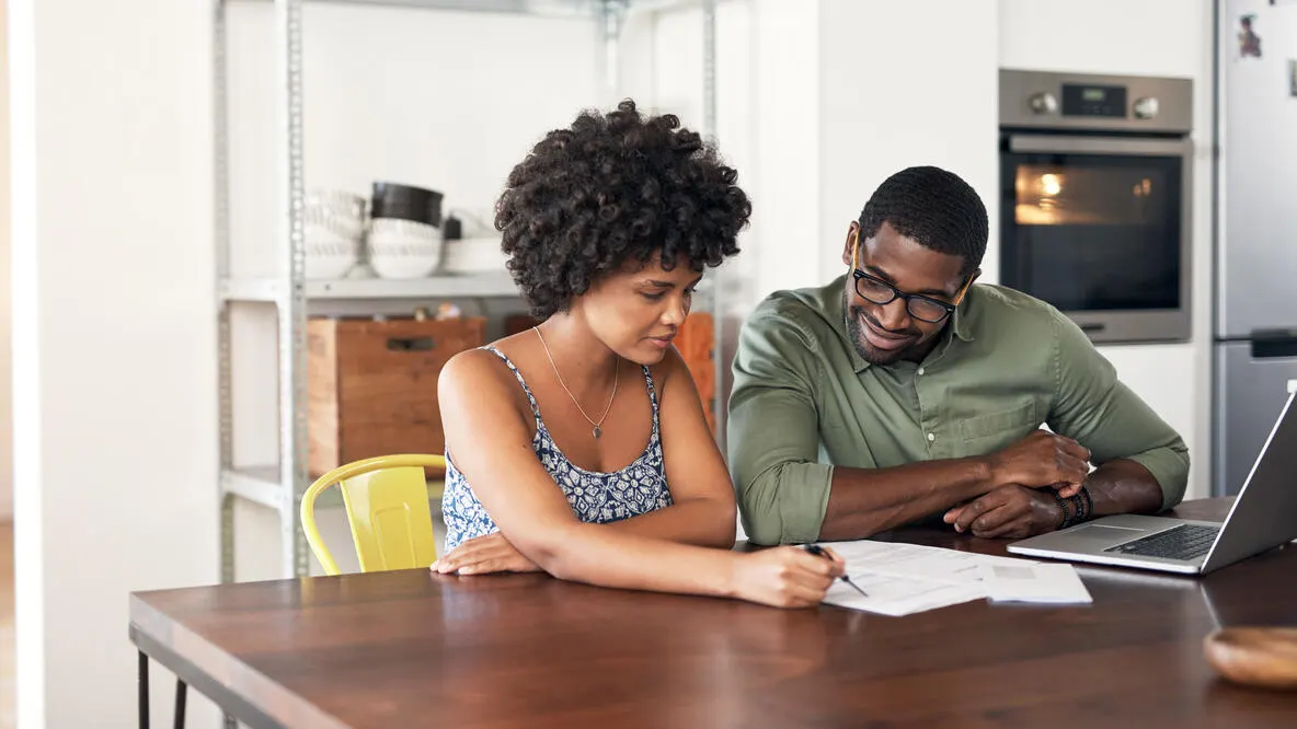 A couple going over documents at the kitchen table.