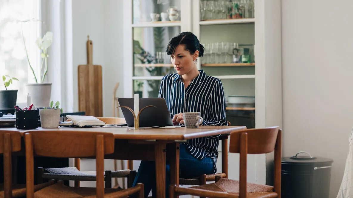 A woman using laptop at a table while working in home office