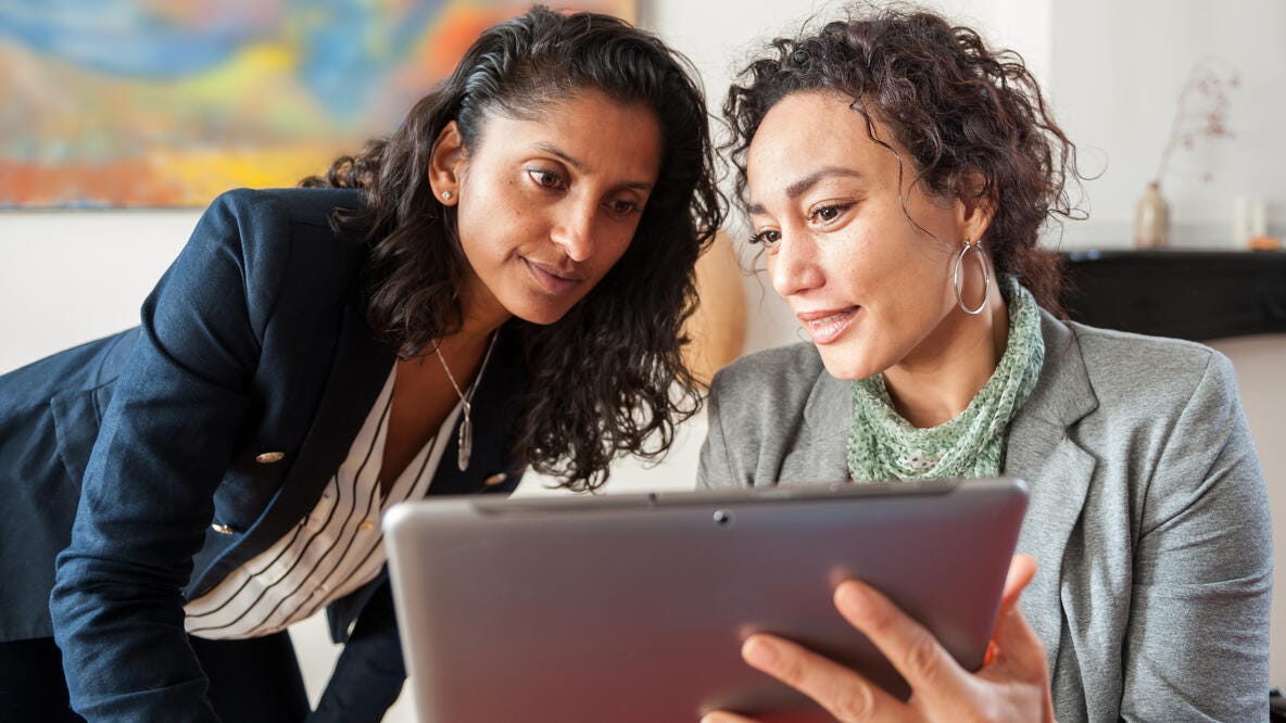 Two business women working on a tablet.
