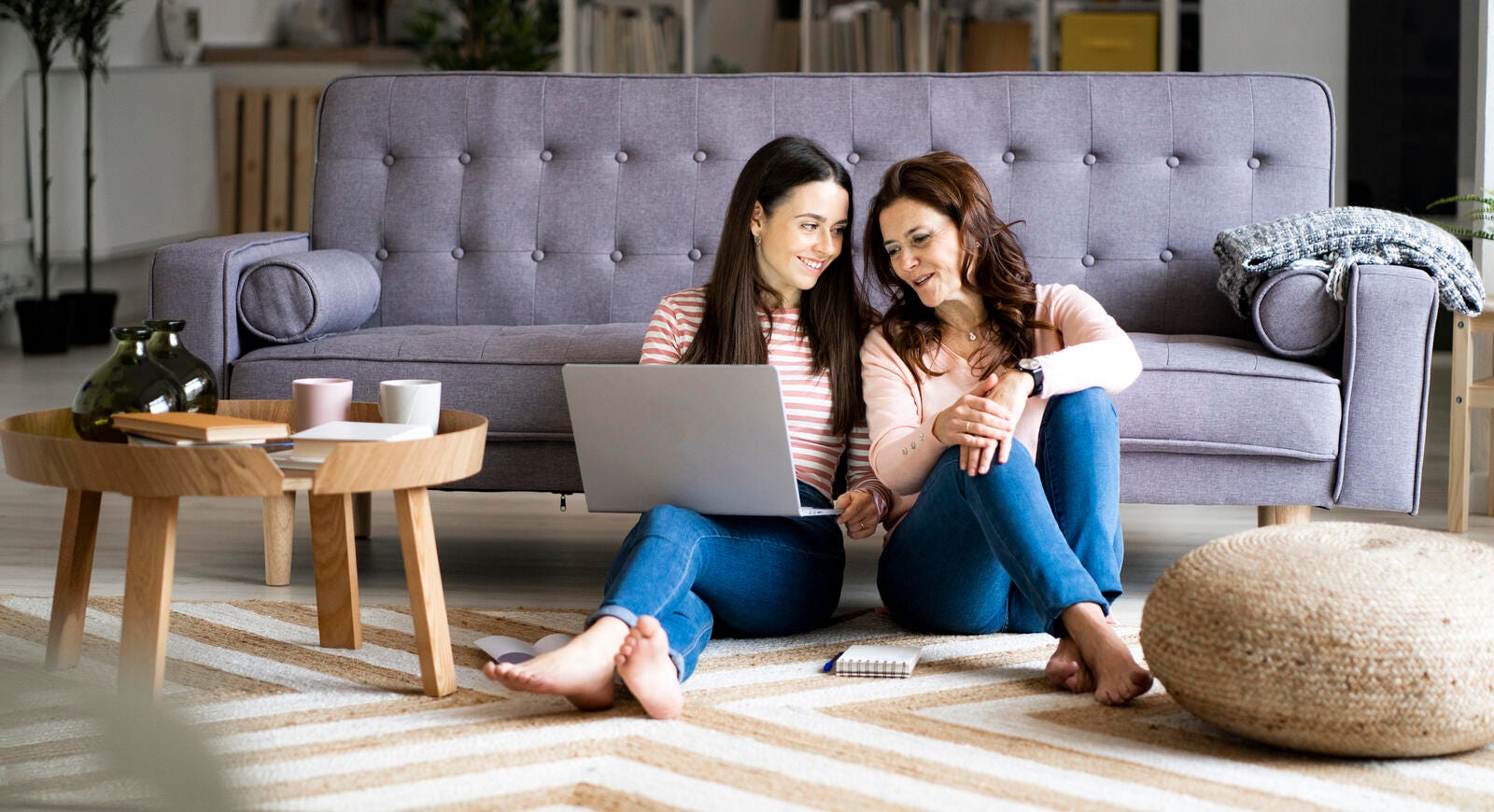 Daughter and mother working together on a laptop in the living room