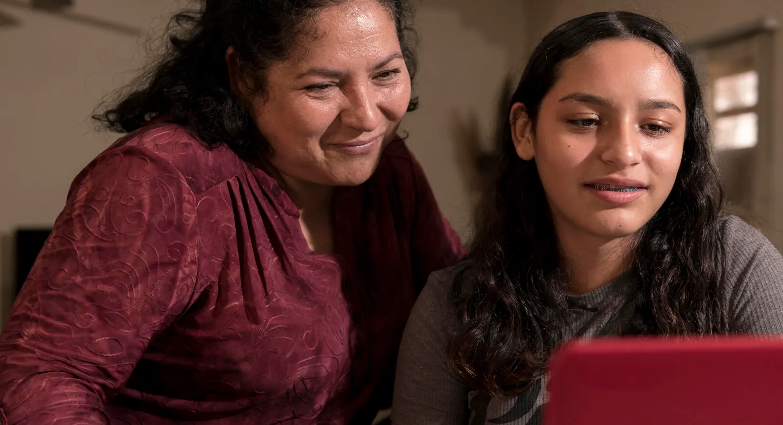 Muchacha usando una Tablet mientras una mujer mayor que ella la asiste