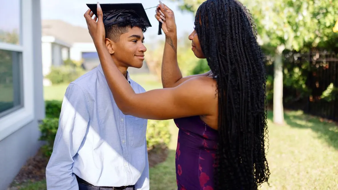 Woman putting graduation cap on man
