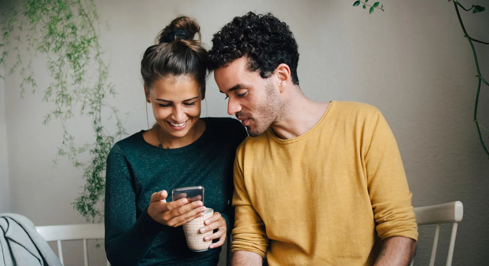 Dos jóvenes adultos usando juntos un teléfono móvil.