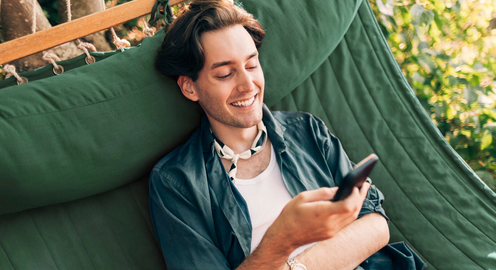 Man looking at phone in hammock