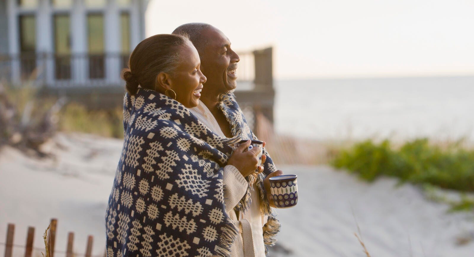 couple wrapped in blanket standing on beach