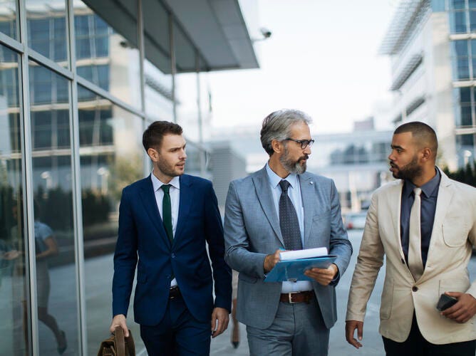 3 men walking down street in suits