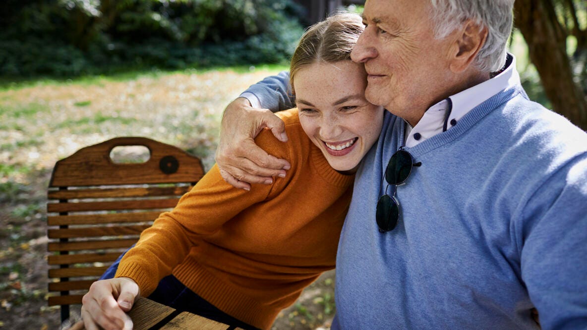 Grandfather and Granddaughter hugging in the park.