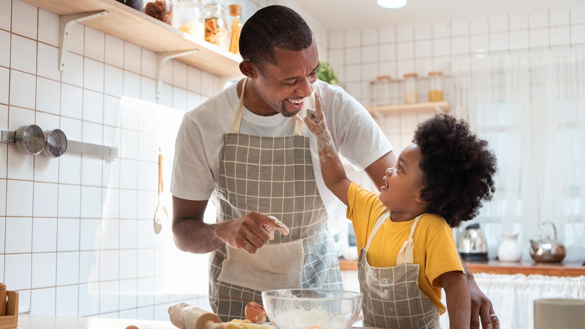 A father is baking in the kitchen with his young son. 