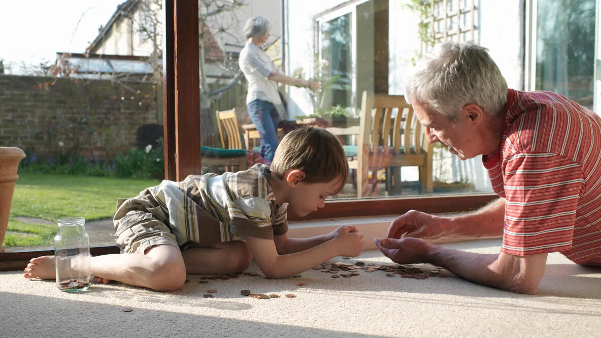 Grandfather and grandson counting change on the floor. 