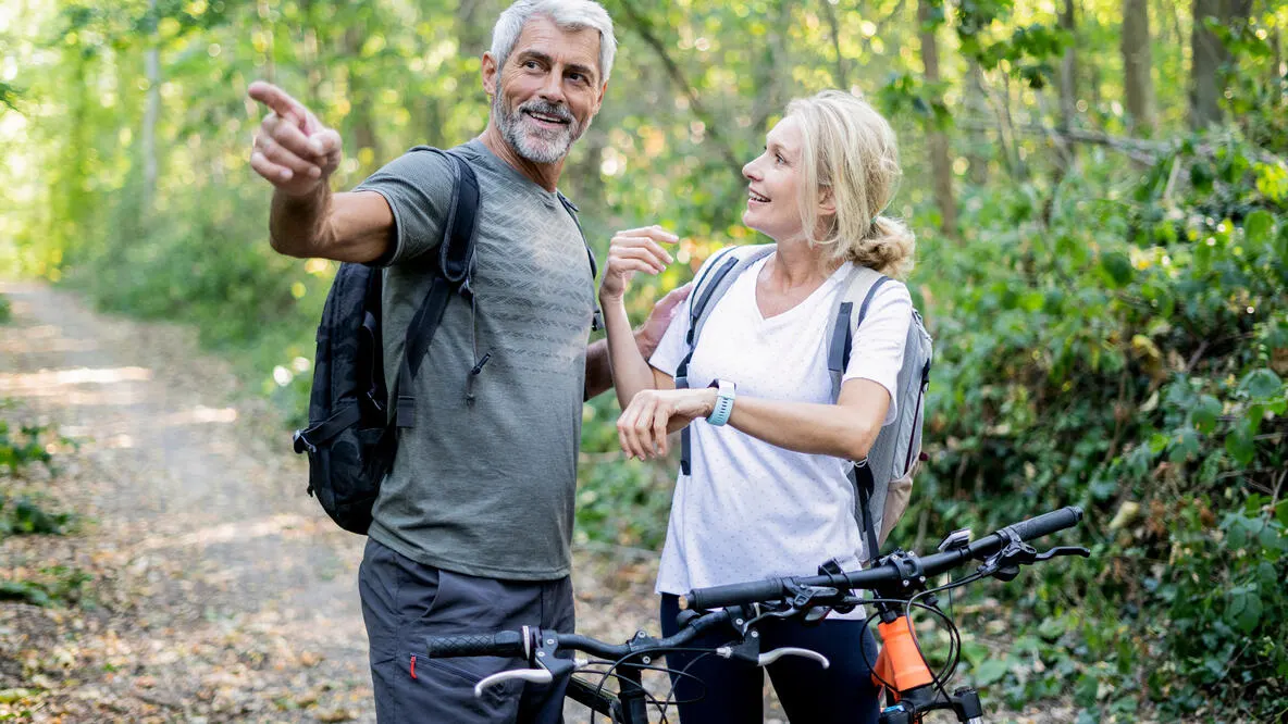 A senior couple taking a break from mountain biking on a trail.