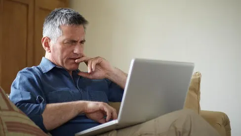 A man using us laptop while sitting on a couch. 