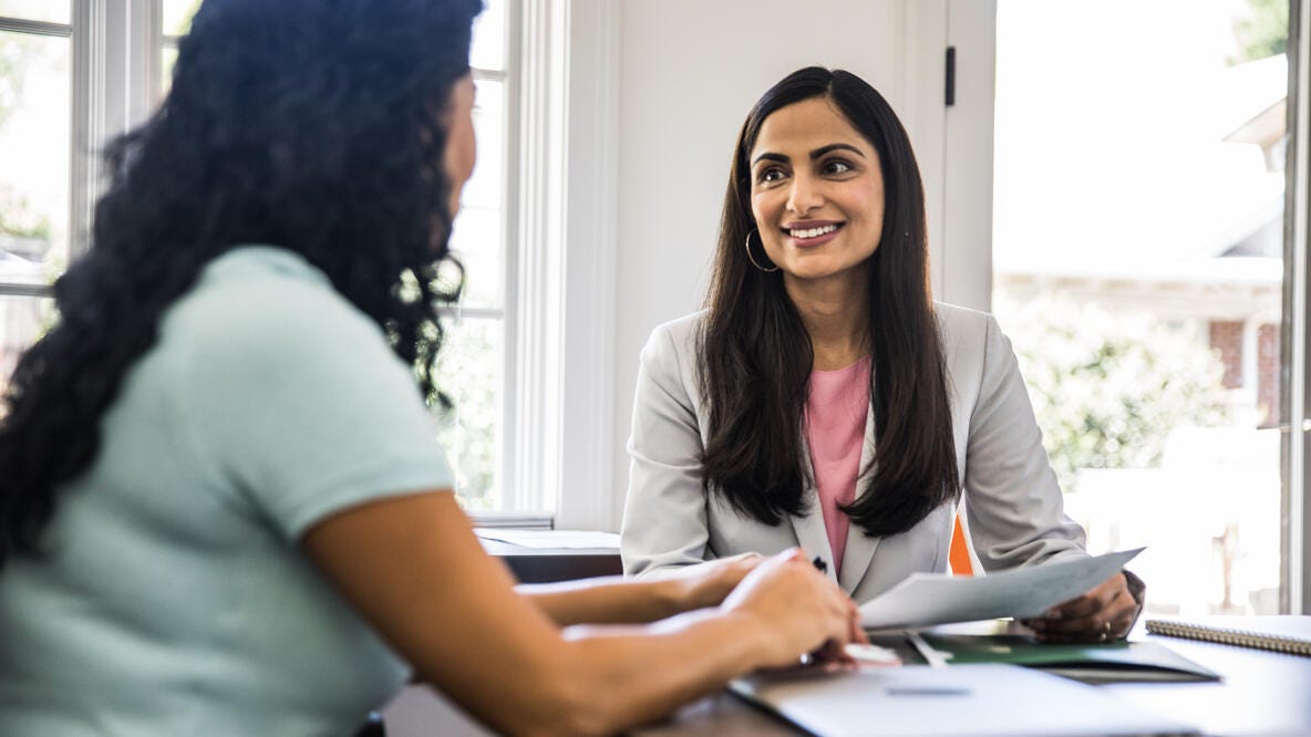 A banker and her customer smiling while reviewing paperwork.