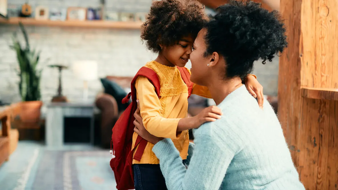 A little girl with a backpack on rubbing noses with her mother.