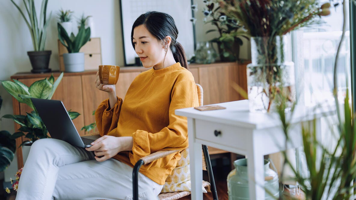 A woman having coffee while looking at her laptop.