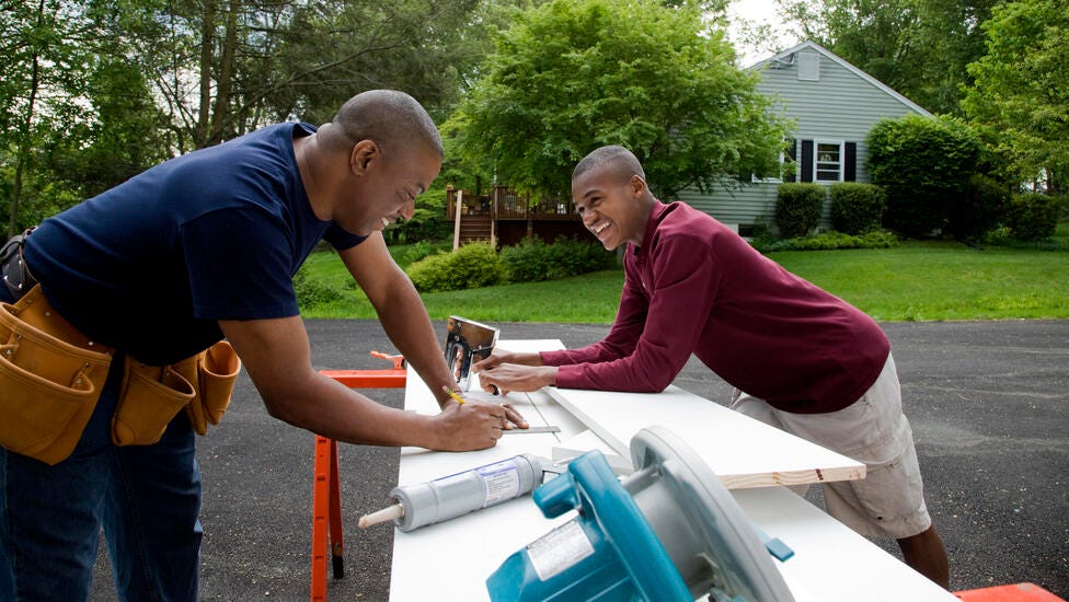 Father and son smiling while doing home renovations.