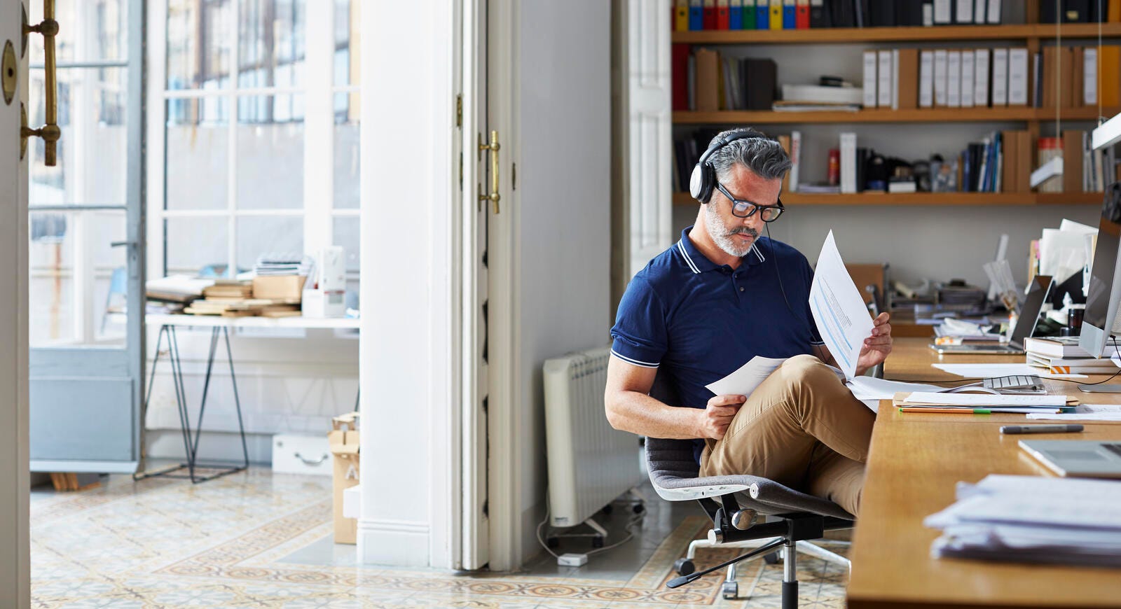 Male examining documents at desk in office