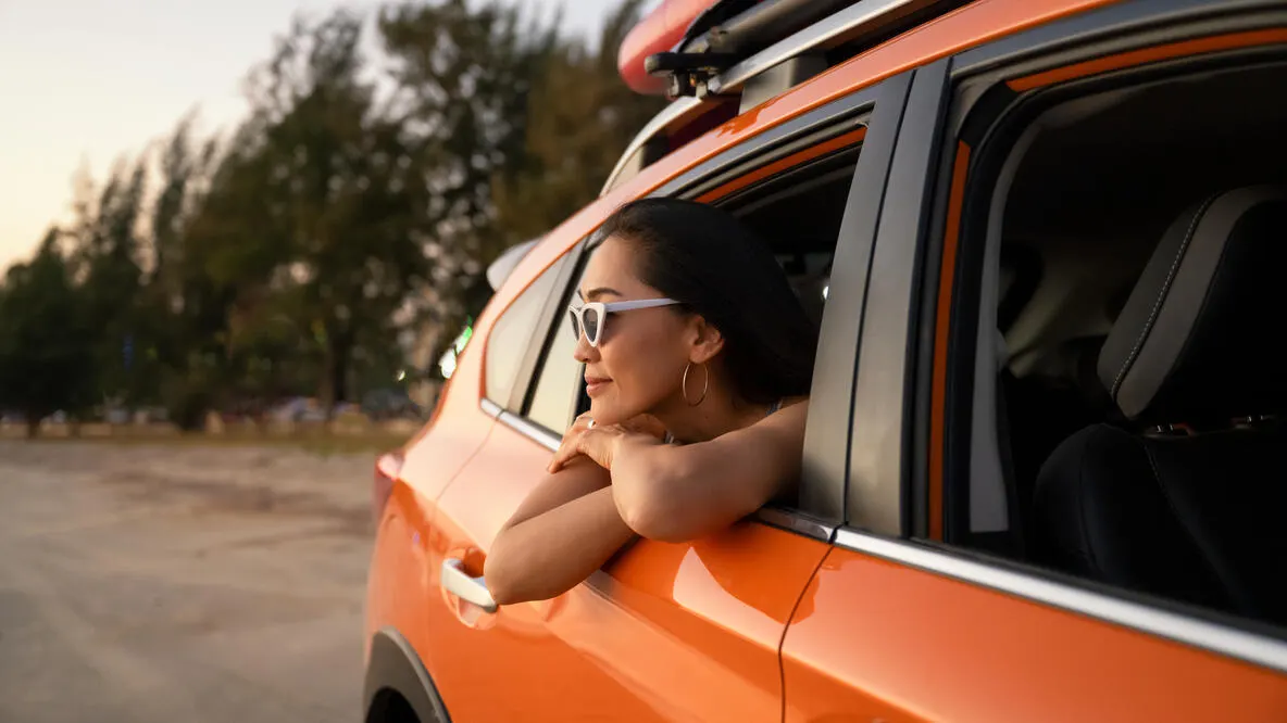 A woman ejoying the breeze through the back window of a car.