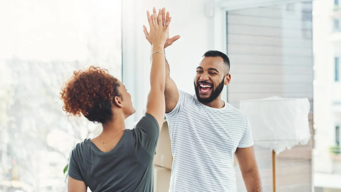 A young couple laughing while giving each other a high five.