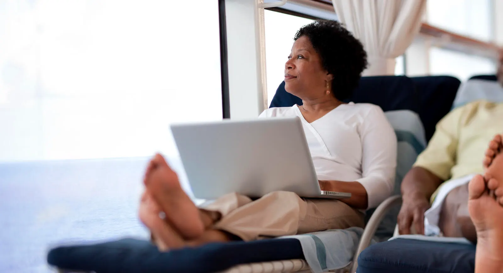 Woman with laptop on her lap looking into distance