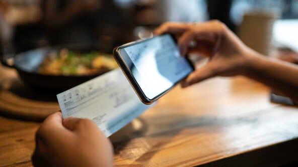 Man depositing a check by mobile phone in a restaurant