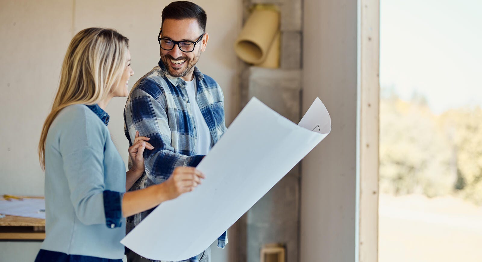 happy couple looking at blueprints